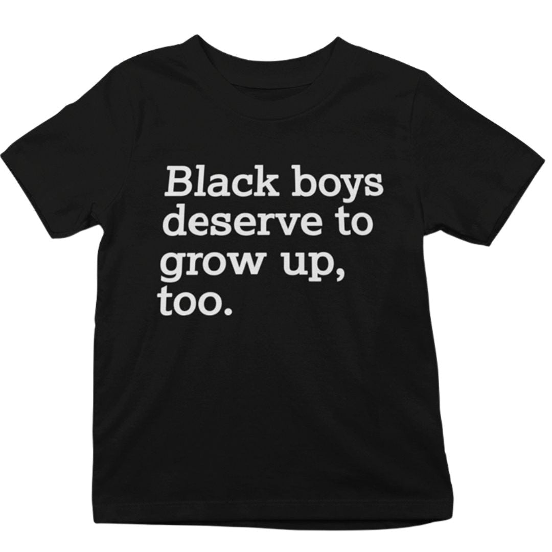 A black short-sleeve t-shirt with the text 'Black boys deserve to grow up, too.' printed in white sans-serif font across the chest, shown against a plain white background.